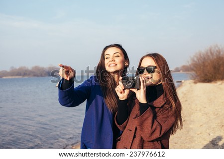Beautiful young girls taking pictures on the beach in front of the sea. Outdoor lifestyle portrait