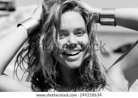 Beauty Sunshine Girl Portrait. Happy Woman Smiling and looking at camera. Sunny Summer Day under the Hot Sun on the Beach. Toned black white Outdoors lifestyle