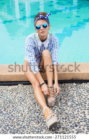 Fashion photo of sexy beautiful Girl in plaid shirt and sunglasses relaxing beside a swimming pool. Outdoors lifestyle  portrait