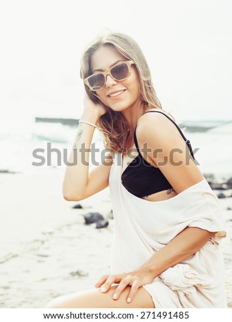 Stunning vintage colorful outdoor summer portrait of pretty young blonde beautiful woman in sunglasses having fun on the beach in windy weather lifestyle trendy colors
