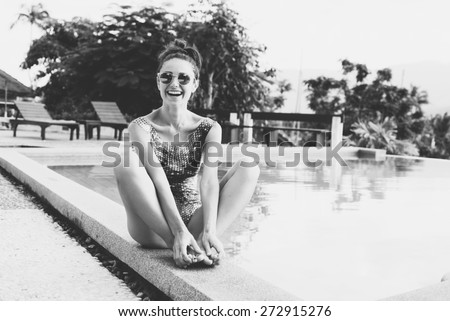 Young pretty woman with perfect tanned body lying on yellow air mattress in the pool in summer and having fun. Outdoor fashion black white  portrait of happy girl