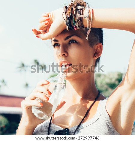 Portrait of young woman drinking water.  Stylish Girl against urban scene