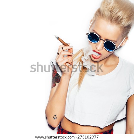 Sexy woman in sunglasses and white t,shirt blowing smoke from a cigar. Swag