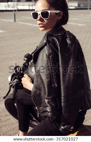 Biker woman sitting on vintage custom motorcycle. Outdoor lifestyle portrait