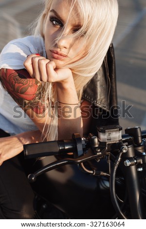 Sexy fashion female biker. Close-up of Woman sitting on vintage custom motorcycle. Outdoor lifestyle portrait