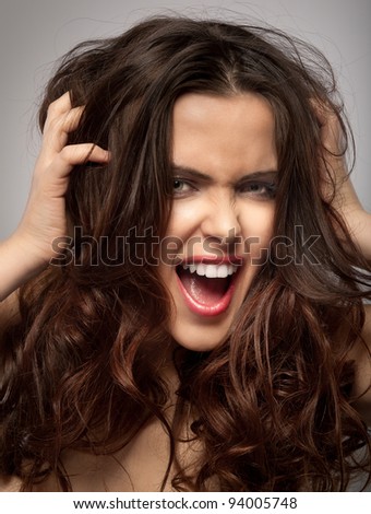 Very frustrated and angry mad woman hands in her hair pulling. Isolated on grey background.