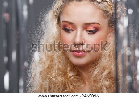 Beautiful blonde looks through the curtains of silver
