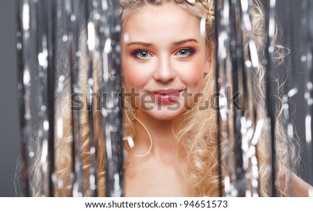 Beautiful blonde looks at the camera through the curtains of silver