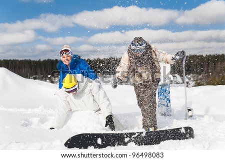 Three young people are having fun on the snow, throwing snow at each other