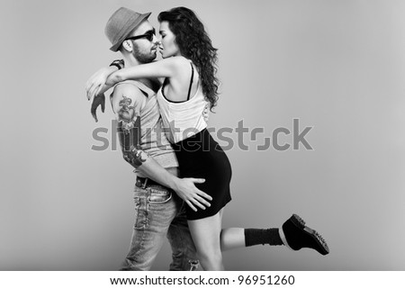 The portrait of a sexy girl and a hot man standing face to face  with his arm round her waist pulling her closer