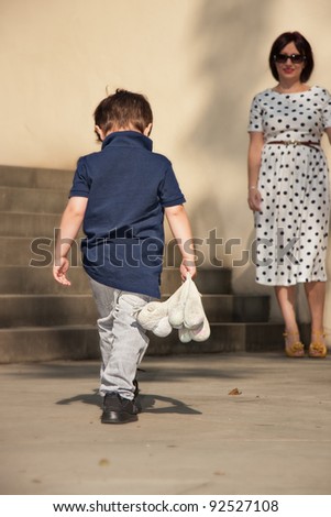 Little boy going with bowed head to Mom