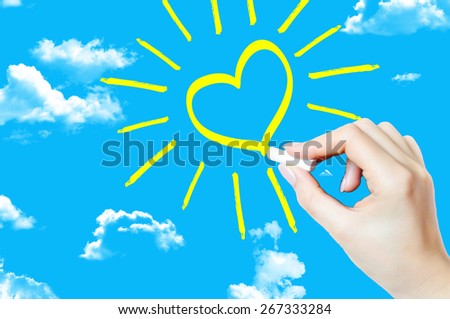 Hand painting a heart shape sun on sky suggesting hope