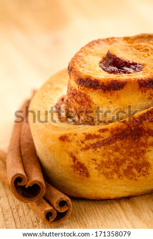 Cinnamon Roll - This is a shot of a tasty cinnamon roll sitting on a wooden table next to a couple cinnamon sticks. Shot with a shallow depth of field.