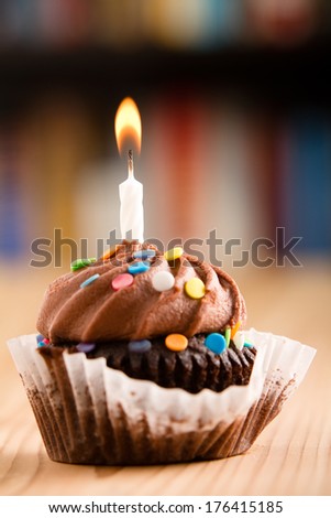 Chocolate Cupcake - This is a shot of a delicious birthday cupcake with a candle sitting on a wooden table top. Shot with a shallow depth of field with the focus on the candle.