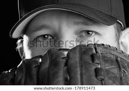 Baseball Player - This is a black and white photo of a young man wearing a baseball cap and looking out over his glove. Shot on an isolated white background and processed slightly to enhance detail.