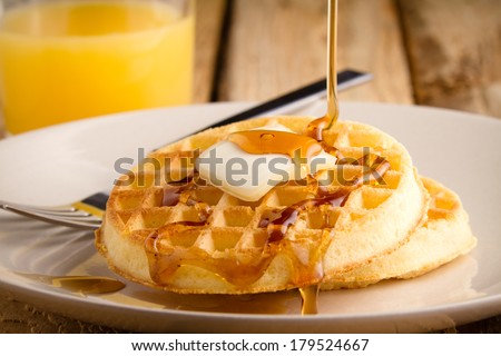 Waffles - This s a photo of a couple waffles being soaked in syrup. Shot on a wooden table with a shallow depth of field.
