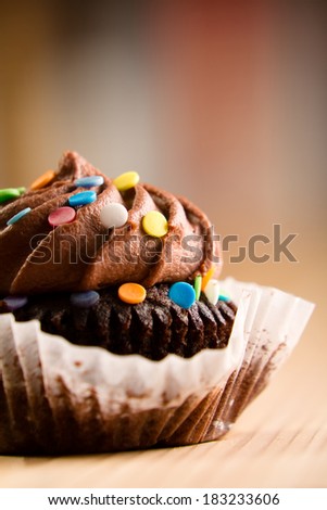 Chocolate Cupcake - This is a shot of a delicious cupcake covered in sprinkles sitting on a wooden table top. Shot with a shallow depth of field.