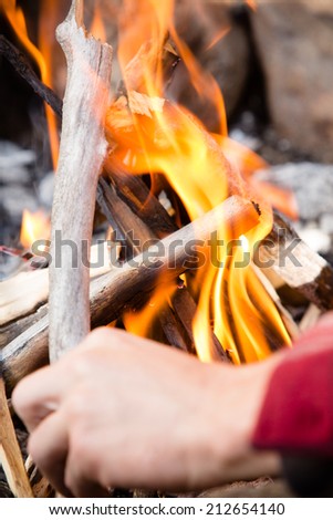 Campfire - This is a shot of a man adjusting a stick on a freshly lit campfire.