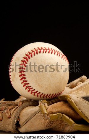 This is a shot of an old baseball sitting on top of an old baseball glove. Shot with a shallow depth of field on a black background.