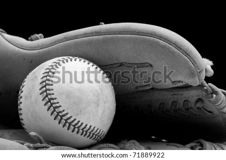 This is a black and white shot of an old baseball in and old baseball glove. Shot with a shallow depth of field on a black background.