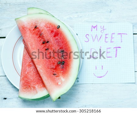 slice of ripe watermelon lying on a plate next to a sheet of paper is labeled \