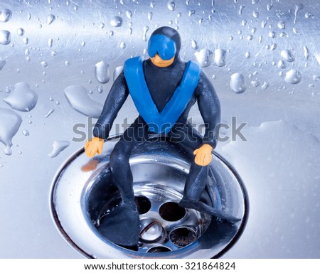 small plasticine diver sitting on a steel sink drain.metaphor.cleaning or repair of water supply system or sewerage