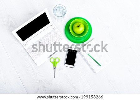 Office supplies, devices, coffee cup and apple on wooden table