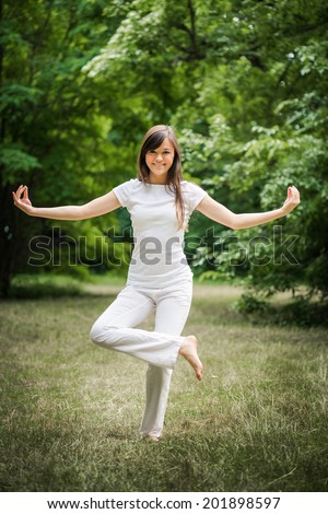 Young woman doing yoga exercise in green park