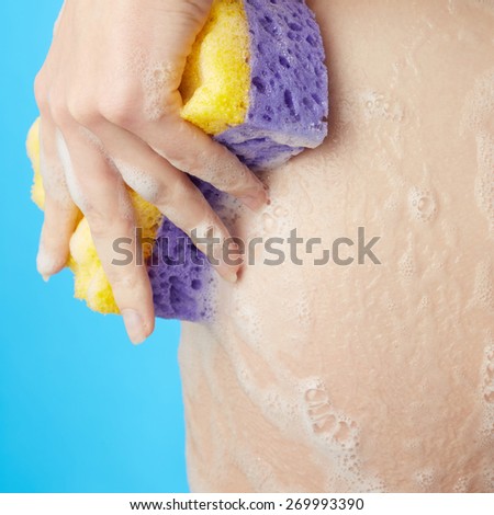 Woman\'s body. Ass in foam of shower gel with wisp of bast on blue background