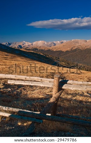 A split rail fence stands against the alpine tundra as the Colorado Rocky Mountains greet the days start in the early morning sunlight
