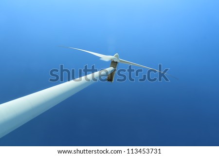 Wind power station with wind turbine as alternative energy source against clear blue sky