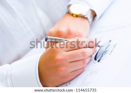 Closeup of a business man holding a pen analyzing pie chart