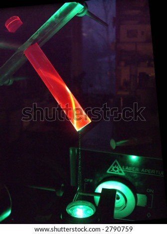 The evening in a lab. Green laser beam excites the red luminescence of a rod of artificial ruby