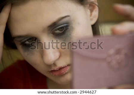 Young girl with weird makeup looking into mirror