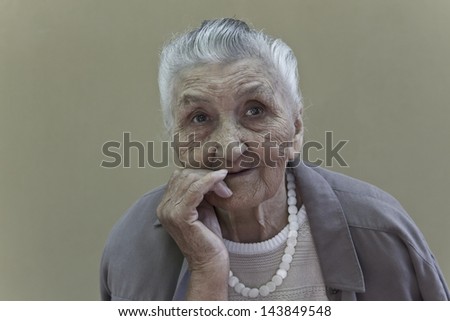 old lady\'s portrait in front of a light brown wall