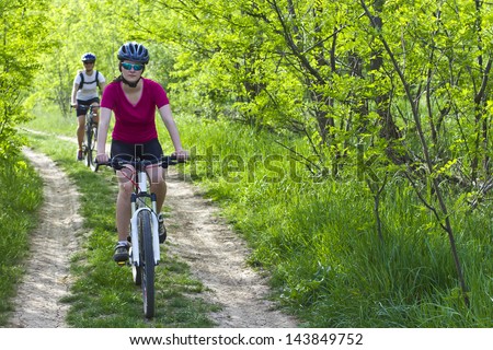 two girls riding the bicycle in the forest