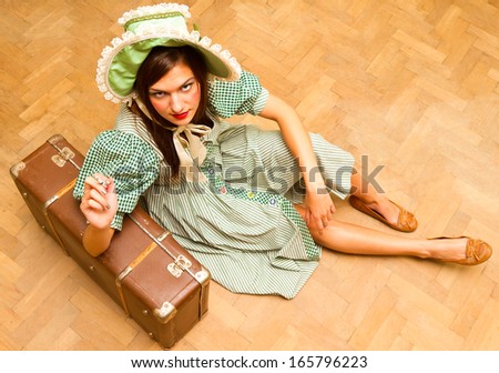 young girl in green dress sitting on the floor with a suitcase, vintage style