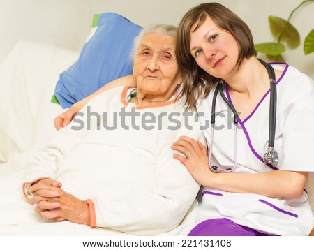 kind young female nurse caring for a very old femaile patient,in hospital