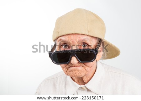 Funny grandma\'s studio portrait  wearing eyeglasses and baseball cap, isolated on white