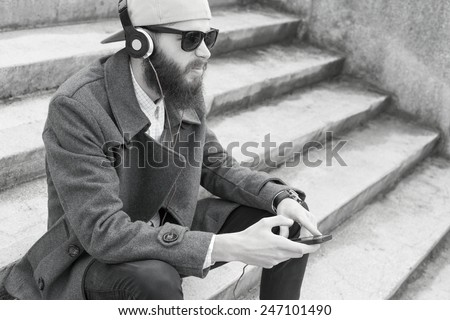 Guy with smartphone and headset listening to music - black and white photograph.