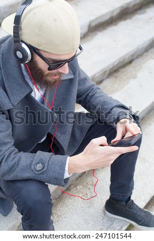 Guy with smartphone and headset listening to music.