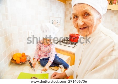 Elderly lady teaching little girl how to cook the best dishes.