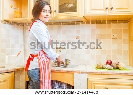 Brunette woman at home preparing food, washing vegetables.