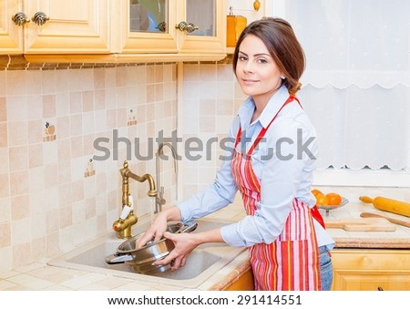 Brunette woman at home preparing food, washing vegetables.
