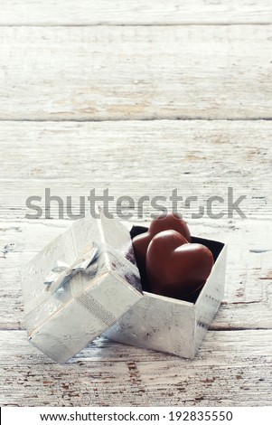 Chocolates in silver gift box over grunge wood background