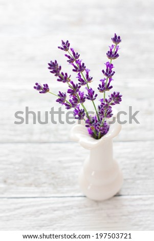Lavender flowers in white vase over wood background
