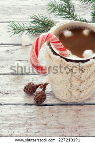 Knitted mug of coffee and red lollipop over white wood background