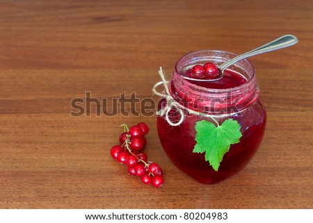 glass pot of currant jam over wooden table