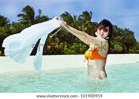 A beautiful fashion asian girl playing water in Maldive beach near the ocean in the hot summer