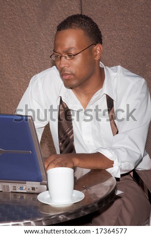 Businessman working notebook laptop computer sitting by the coffee table of some cafe outdoors